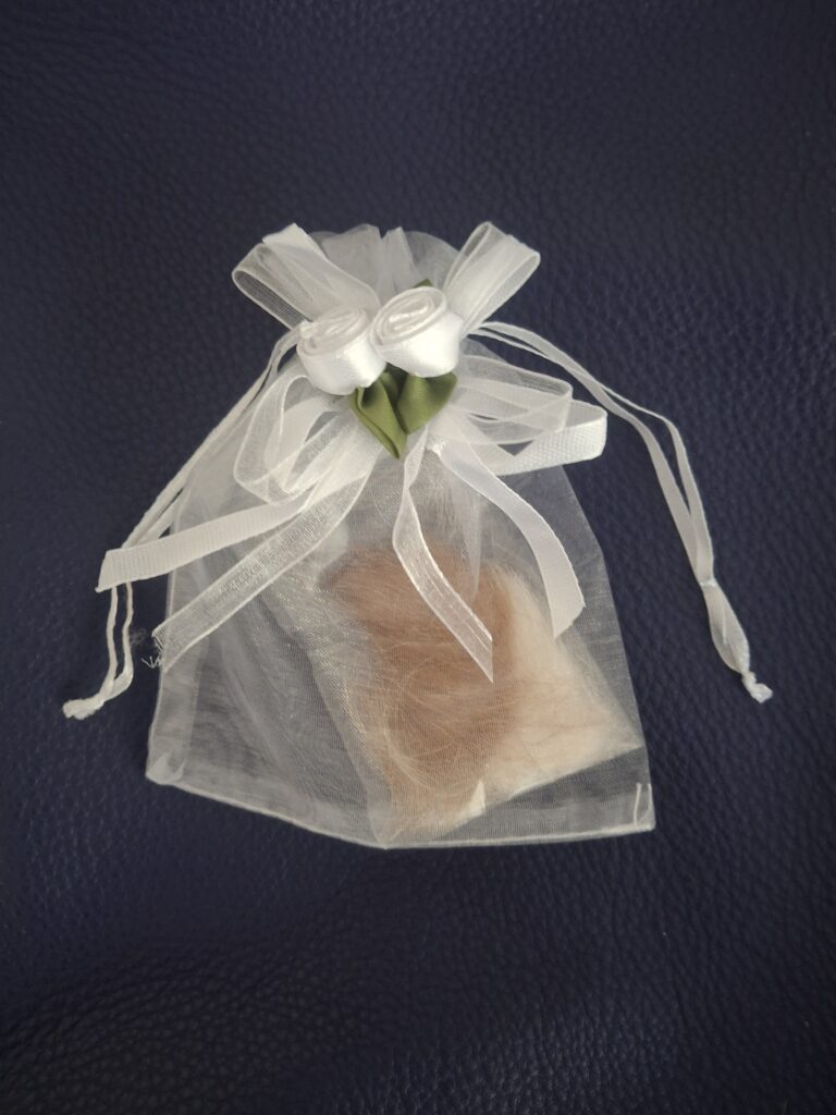 Lock of fur in a white organza keepsake bag